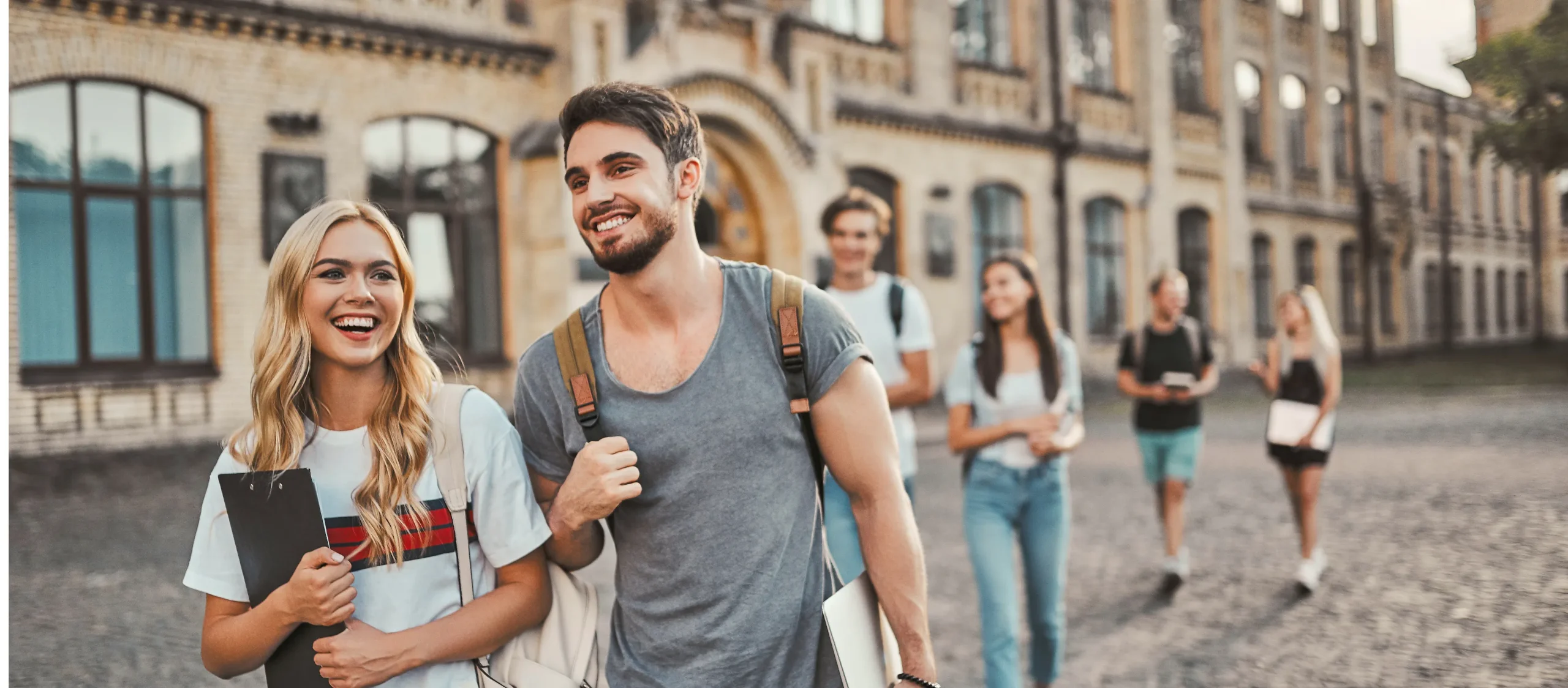 Eine Studentin und ein Student gehen über den Hof ihrer Universität.