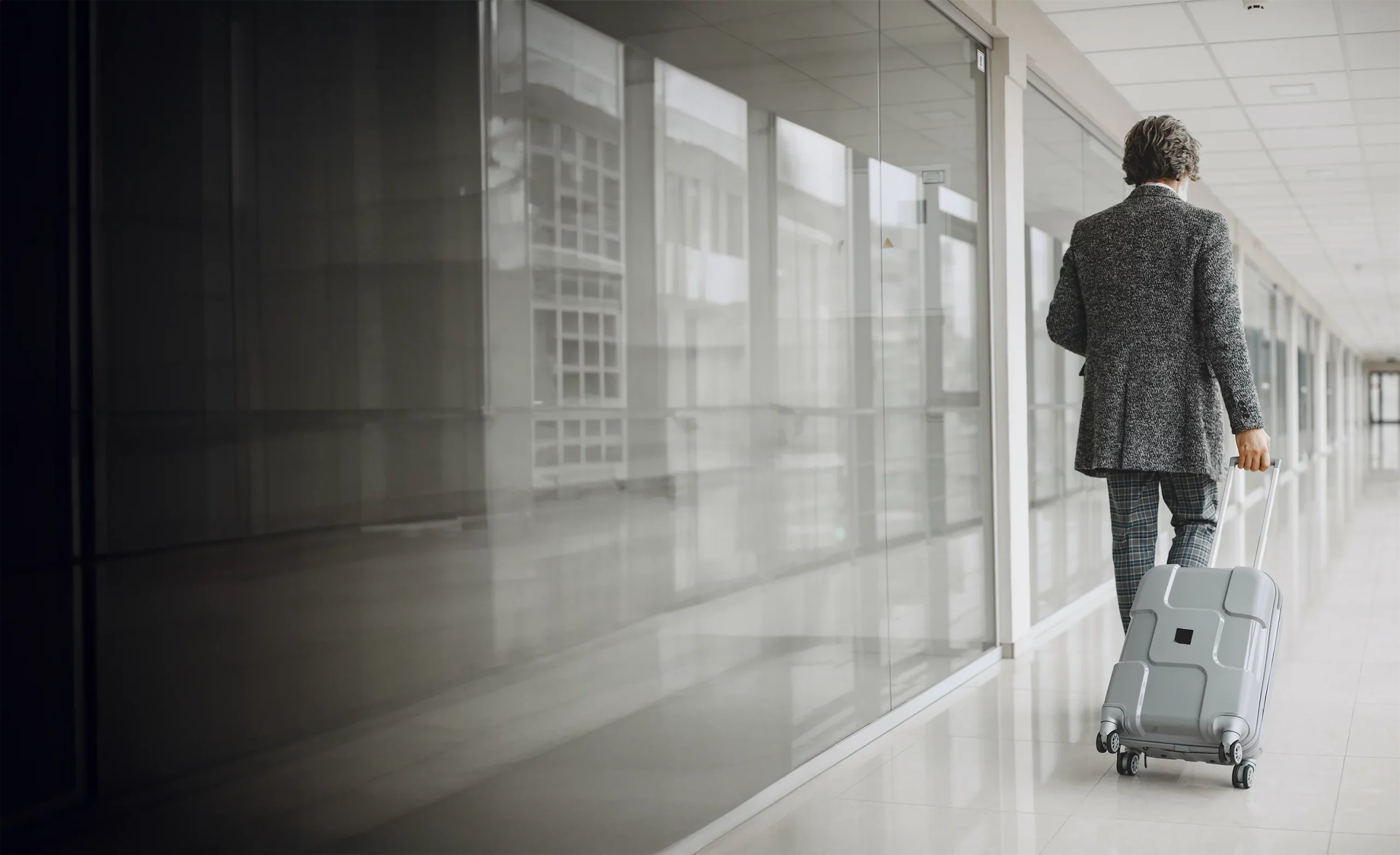 A man is walking through the airport with his suitcase for a business trip.