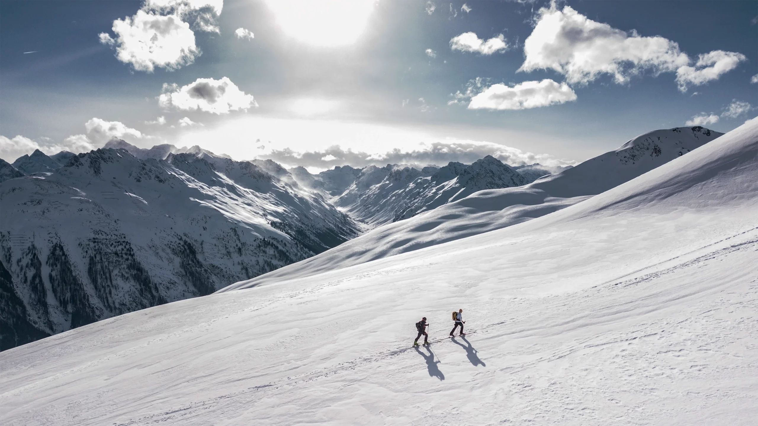 Zwei Personen gehen gemeinsam durch eine verschneite Ebene inmitten der Schweizer Alpen.