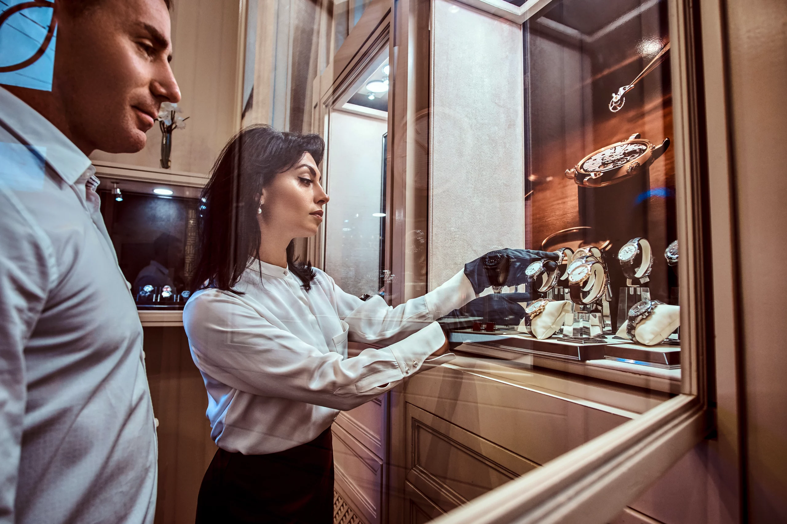 Eine Ausstellerin nimmt während einer Ausstellung eine Uhr aus der Vitrine.